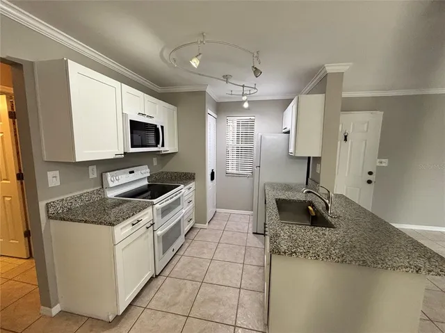 a kitchen with granite countertop a sink a counter top space appliances and cabinets
