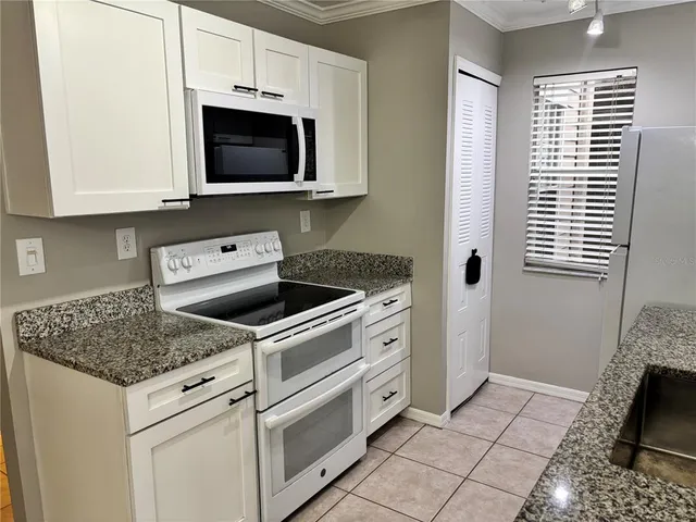 a kitchen with granite countertop a stove top oven microwave and cabinets