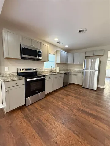 a view of an empty room with wooden floor and window
