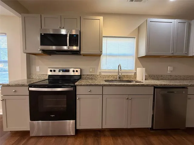 a kitchen with granite countertop a refrigerator sink and cabinets