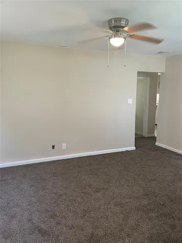 a view of an empty room and a chandelier fan