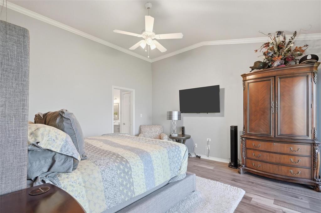 1904 Signal Ridge Place Rockwall, TX 75032 - Photo 15 of 23 Bedroom with crown molding, light wood-style flooring, lofted ceiling, connected bathroom, and ceiling fan