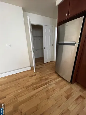 an empty room with wooden floor and a refrigerator