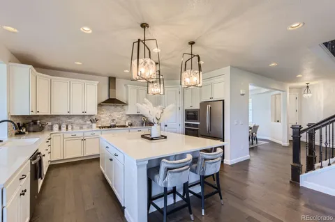 a kitchen with a sink a stove a refrigerator and chairs