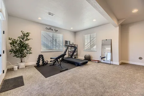 a living room with furniture gym equipment and large windows