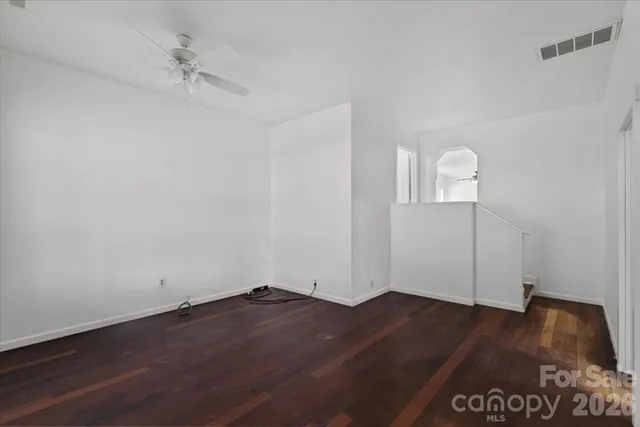 an empty room with wooden floor and fan