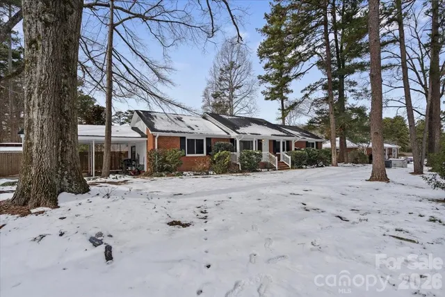 a front view of a house with a dirt road and trees