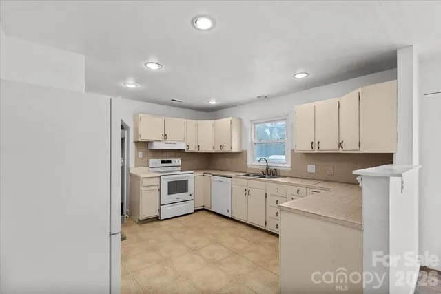 a kitchen with granite countertop white cabinets and white appliances