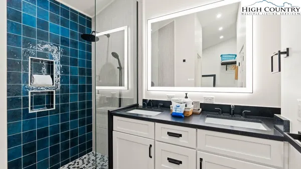 a bathroom with a double vanity sink a mirror and a shower