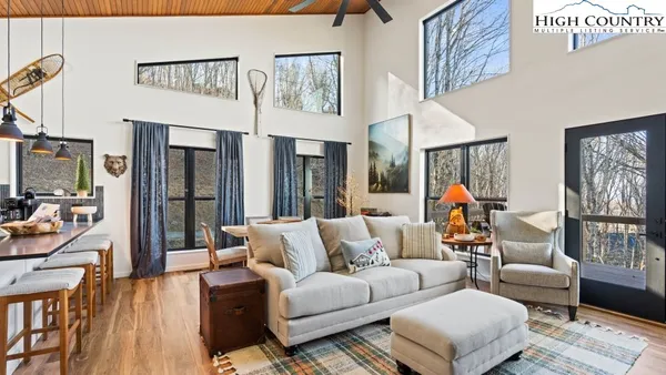 a living room with furniture a flat screen tv and a floor to ceiling window