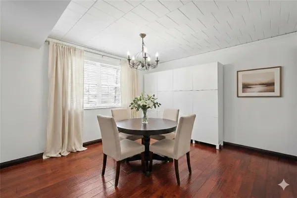 a dining room with furniture wooden floor a potted plant and a chandelier