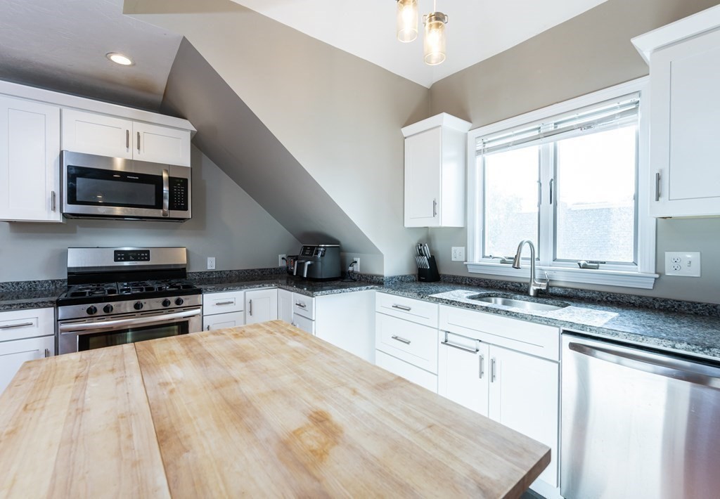 8 Putnam Street, Unit 3 Danvers, MA 01923 - Photo 9 of 32 a kitchen with stainless steel appliances a stove sink microwave and cabinets