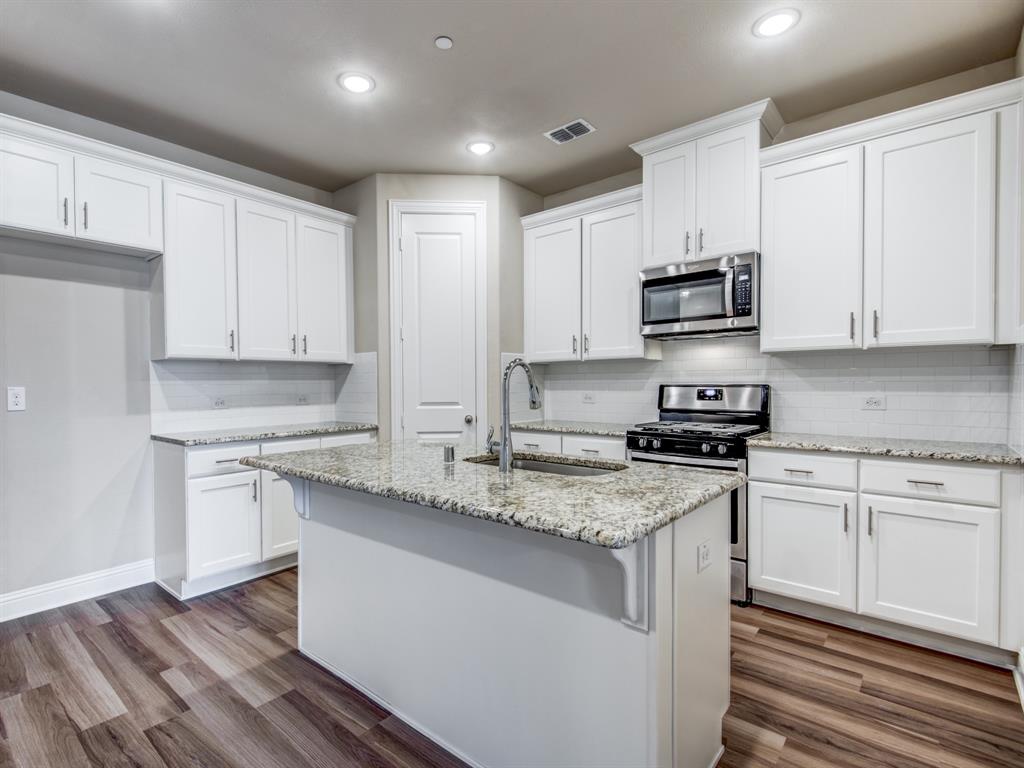 a kitchen with stainless steel appliances granite countertop a sink stove a microwave and cabinets