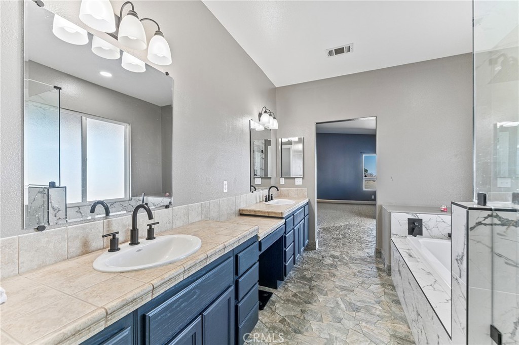 2700 Olivera Road Pinon Hills, CA 92371 - Photo 20 of 37 a spacious bathroom with a granite countertop double vanity sink a mirror and shower