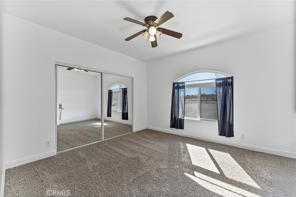2700 Olivera Road Pinon Hills, CA 92371 - Photo 22 of 37 an empty room with chandelier fan and windows