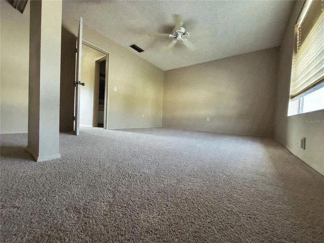 a view of a big room with windows and chandelier fan