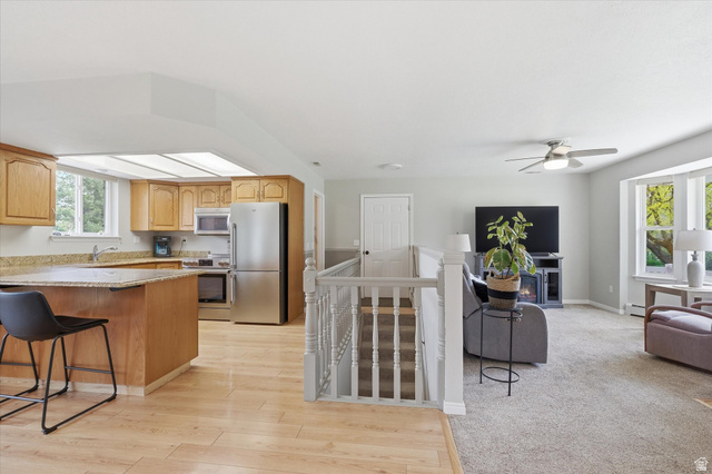 45 West 100 South Mendon, UT 84325 - Photo 13 of 64 Kitchen with stainless steel appliances, a breakfast bar, light stone counters, light wood finished floors, and ceiling fan