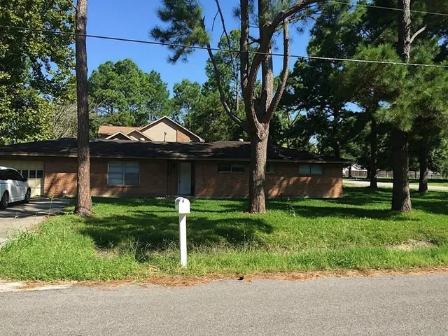 a front view of house with a garden and trees