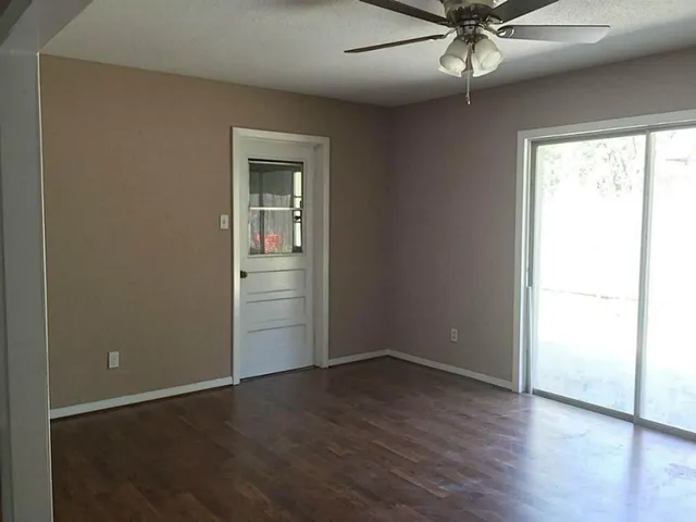 an empty room with wooden floor closet and windows