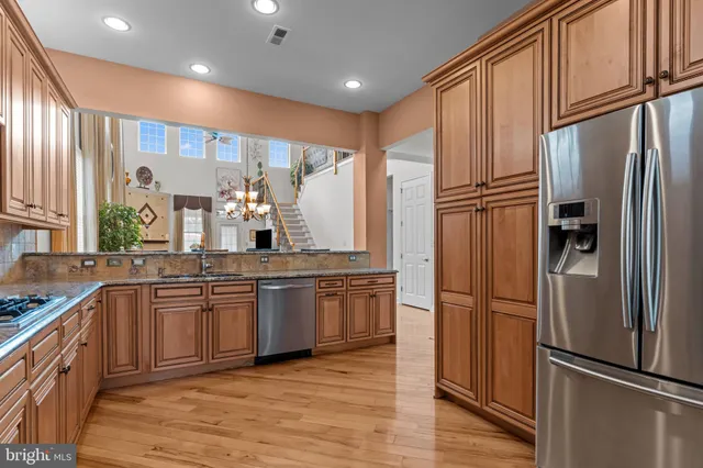 a kitchen with stainless steel appliances granite countertop a refrigerator a sink a stove and cabinets