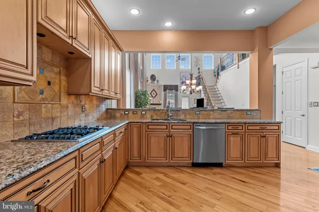 a kitchen with stainless steel appliances granite countertop wooden cabinets a sink and dishwasher a oven with wooden floor