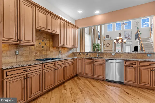 a kitchen with stainless steel appliances granite countertop furniture wooden floor and a window