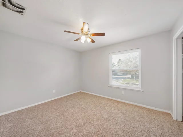an empty room with a window and a ceiling fan