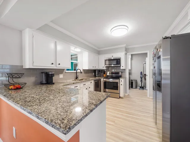 a kitchen with stainless steel appliances granite countertop a sink refrigerator and cabinets