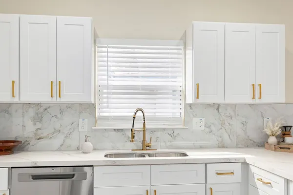 a kitchen with granite countertop white cabinets and white appliances
