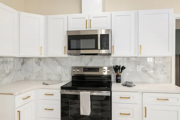 a kitchen with granite countertop white cabinets and stainless steel appliances