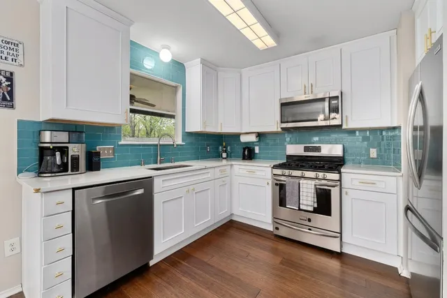 a kitchen with white cabinets stainless steel appliances and wooden floor