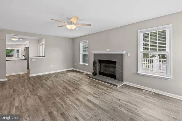 a view of an empty room with wooden floor fireplace and a window
