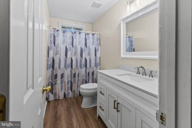 a bathroom with a granite countertop toilet a sink and a mirror
