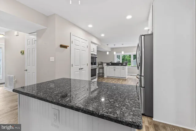 a view of a kitchen with refrigerator stove and wooden floor