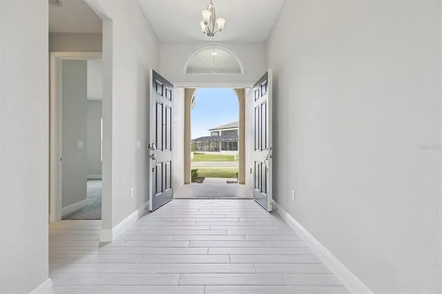a view of a hallway with wooden floor and a chandelier