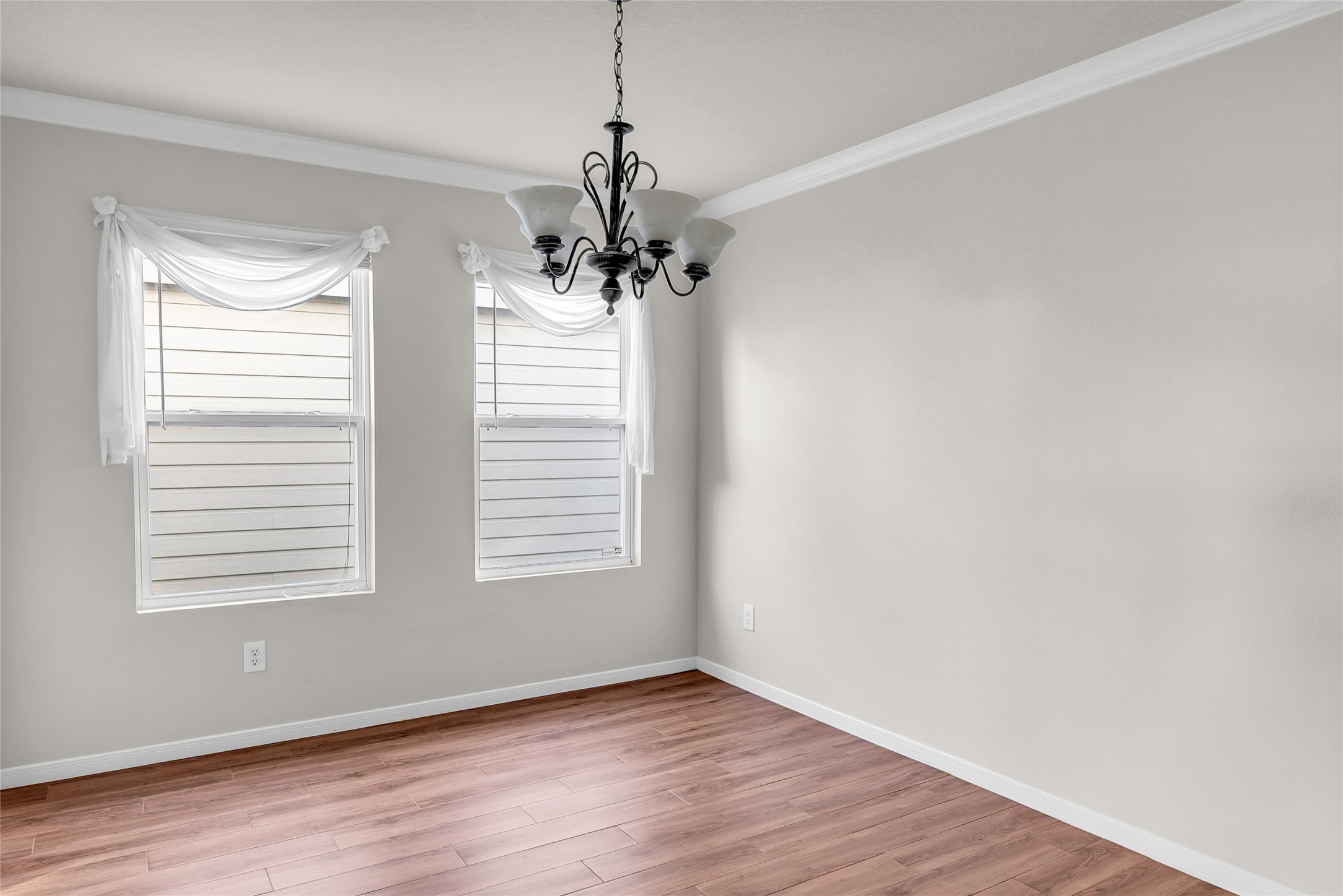 5018 Mabry Stream Court Katy, TX 77449 - Photo 17 of 31 Bright dining room, featuring two windows adorned with sheer drapes. A classic chandelier hangs from the ceiling, complementing the neutral wall tones for an elegant touch.