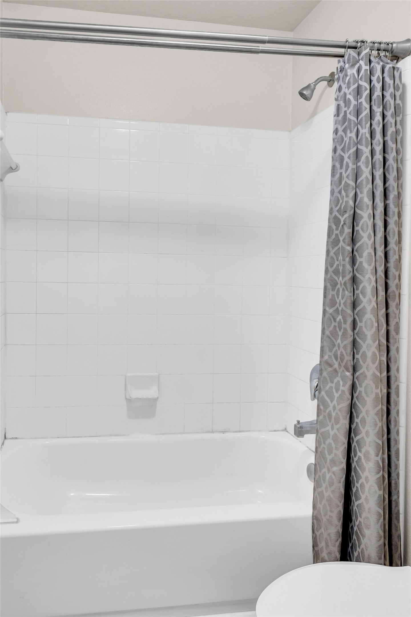 5018 Mabry Stream Court Katy, TX 77449 - Photo 20 of 31 This bathroom features a clean, white-tiled shower and tub combo with a modern, patterned shower curtain. Perfect for a sleek and simple design.