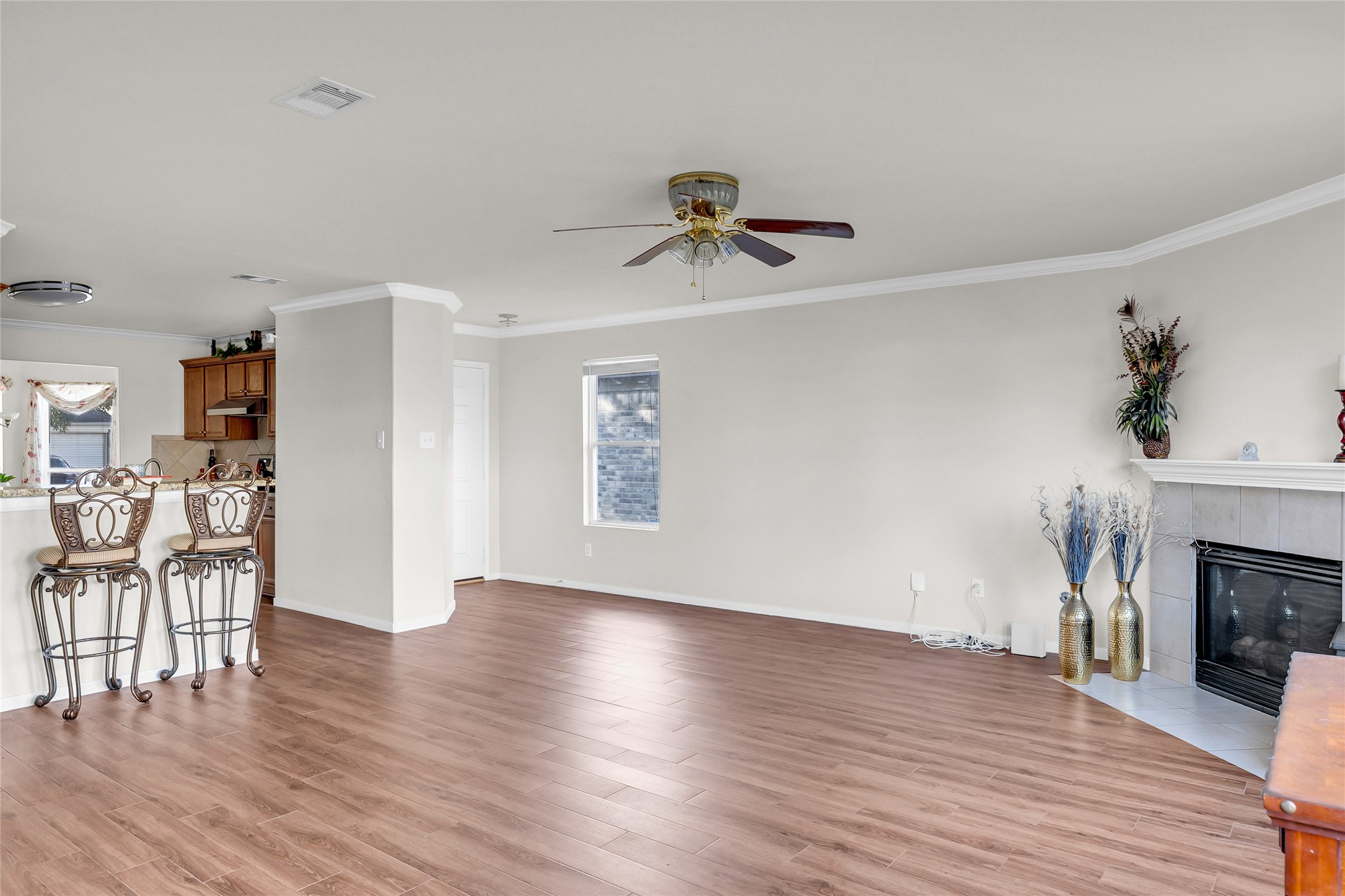 5018 Mabry Stream Court Katy, TX 77449 - Photo 5 of 31 This spacious living area features LVP flooring, a cozy fireplace, and an open layout with a breakfast bar connecting to the kitchen. It has neutral walls, ceiling fan, and ample natural light, offering a welcoming and versatile space.