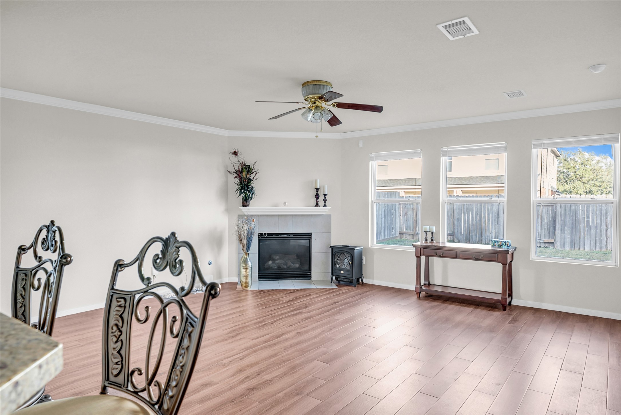 5018 Mabry Stream Court Katy, TX 77449 - Photo 6 of 31 Bright and spacious living room with LVP flooring, a cozy fireplace, and large windows offering plenty of natural light. Features decorative molding and a ceiling fan for comfort. Ideal for relaxation and entertaining.