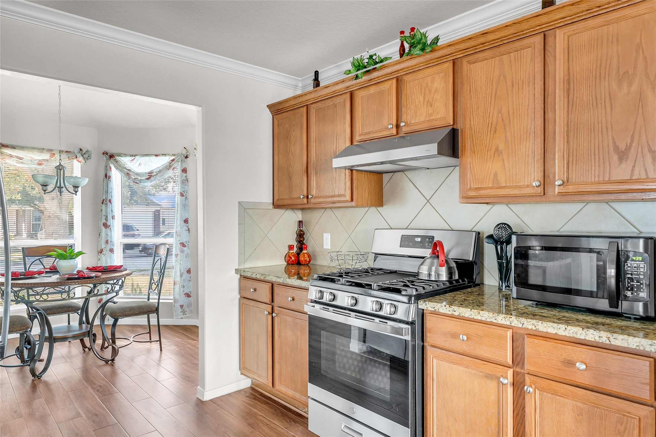 5018 Mabry Stream Court Katy, TX 77449 - Photo 9 of 31 This kitchen features warm wood cabinets, granite countertops, and a stainless steel gas stove. It opens to a cozy dining area with large windows that let in plenty of natural light.