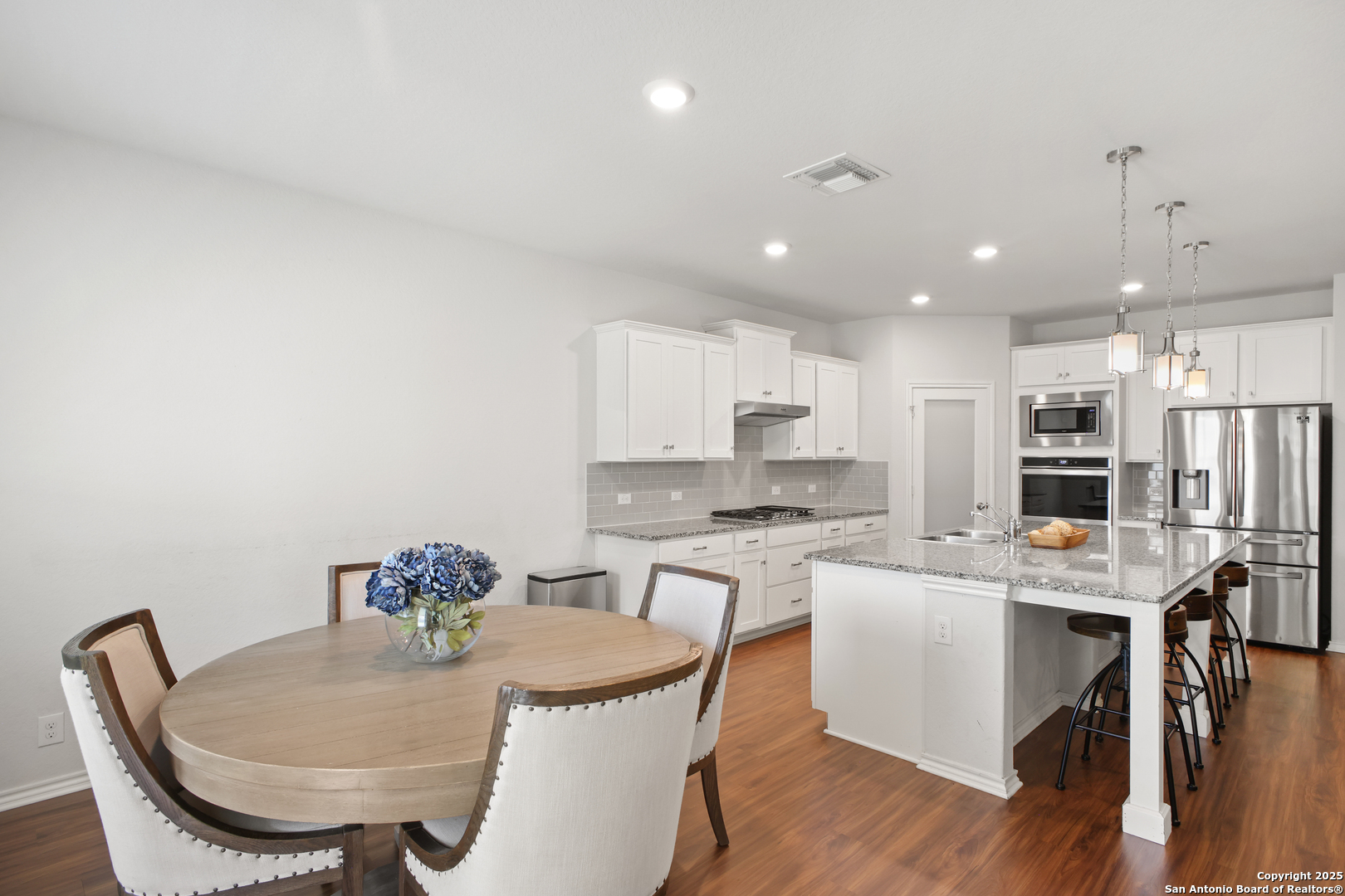 6908 Opus Lane Converse, TX 78109 - Photo 14 of 41 a kitchen with stainless steel appliances kitchen island granite countertop a stove a sink a dining table and chairs