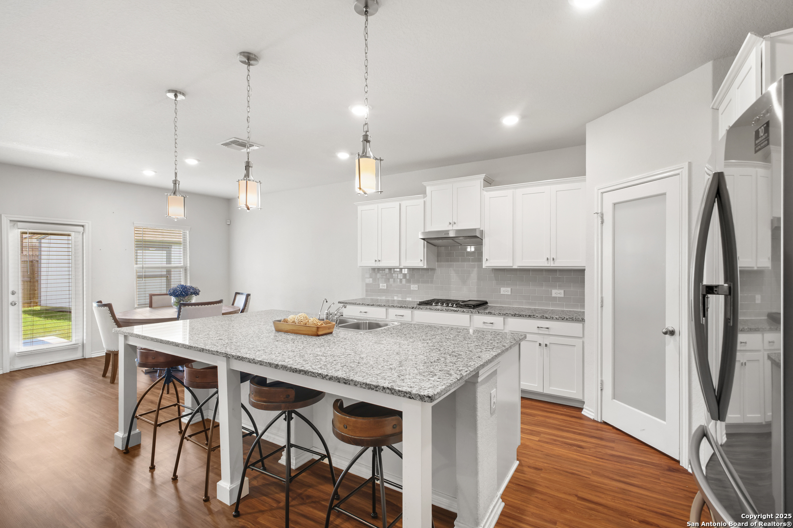 6908 Opus Lane Converse, TX 78109 - Photo 16 of 41 a open kitchen with stainless steel appliances granite countertop a kitchen island a stove a table and chairs in it