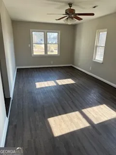 an empty room with wooden floor fan and windows