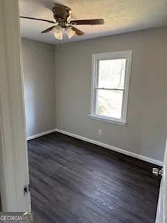an empty room with wooden floor closet and windows