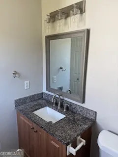 a bathroom with a granite countertop sink a toilet and mirror
