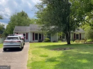 a front view of a house with a garden and trees