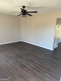 a view of a room with wooden floor and a ceiling fan