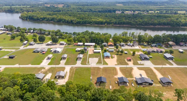 an aerial view of a residential houses with outdoor space and lake view