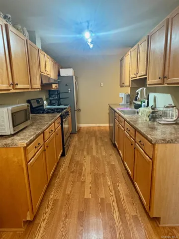 a kitchen with stainless steel appliances kitchen island granite countertop a sink stove cabinets and wooden floor