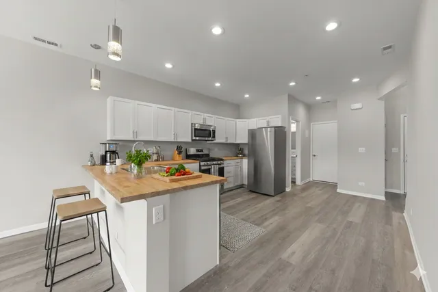 a kitchen with stainless steel appliances granite countertop a refrigerator sink and white cabinets